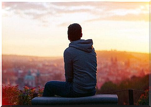 Lonely boy sitting on bench looking at panorama