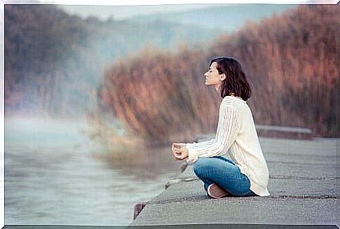 Woman meditates at the lake managing stress