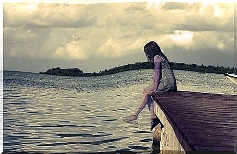 Girl on the dock with dangling feet.