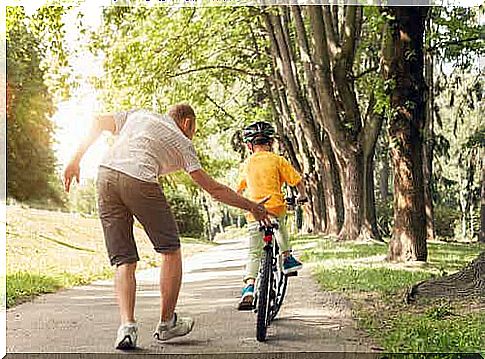 Father teaching his son to ride a bicycle.