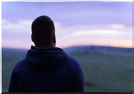 Boy watches the sunset from behind.